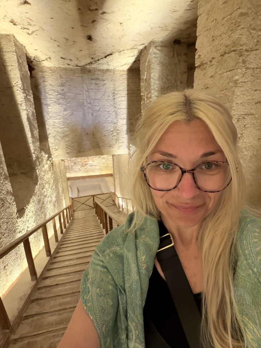 Rebecca smiling inside a stone-lined interior