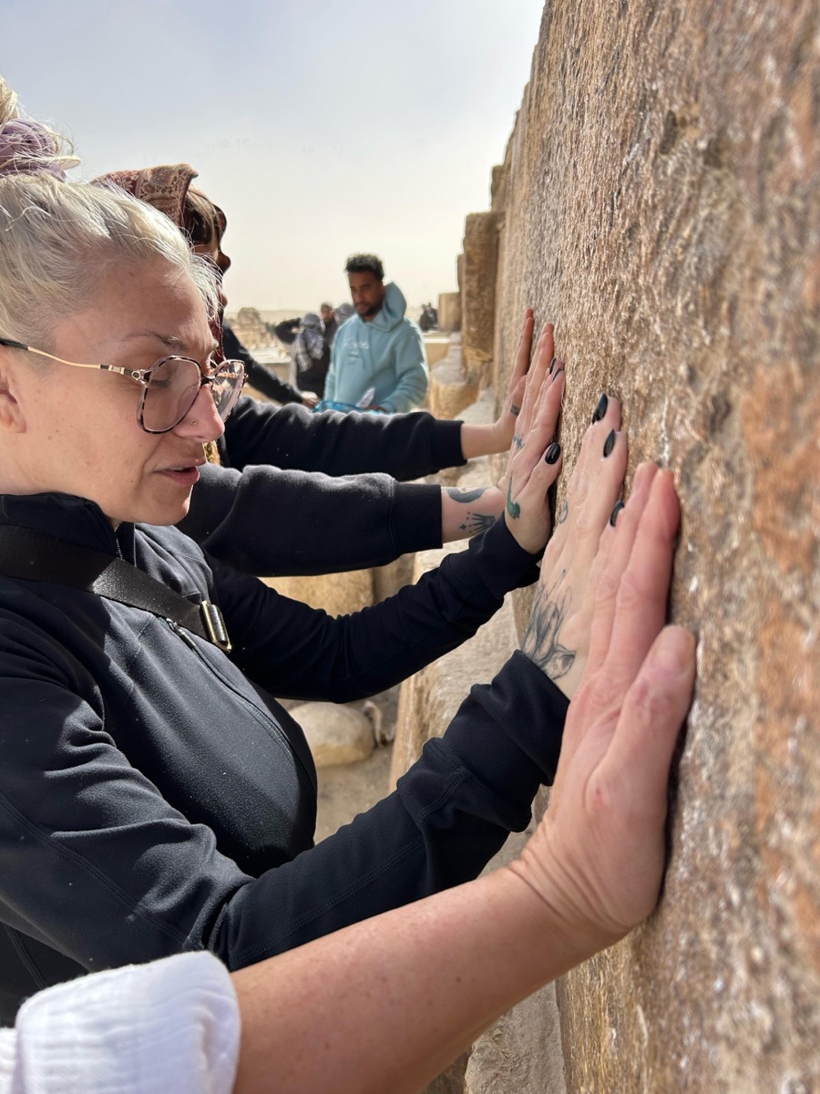Rebecca and other retreat participants resting their hands on a stone wall